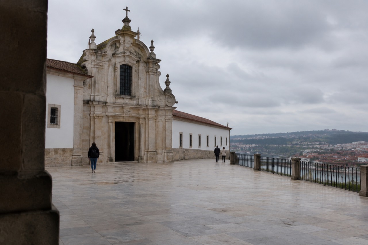 The baroque portal and stone facade of a small chapel beside a university courtyard in Coimbra
