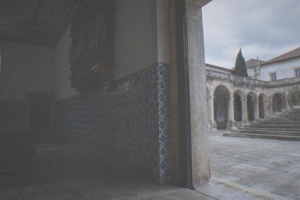 An old stone courtyard with arcades and worn steps under a bright sky in a Portuguese university