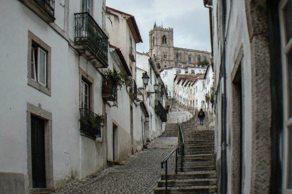 A steep cobbled street in Coimbra's upper town with cathedral stone visible above