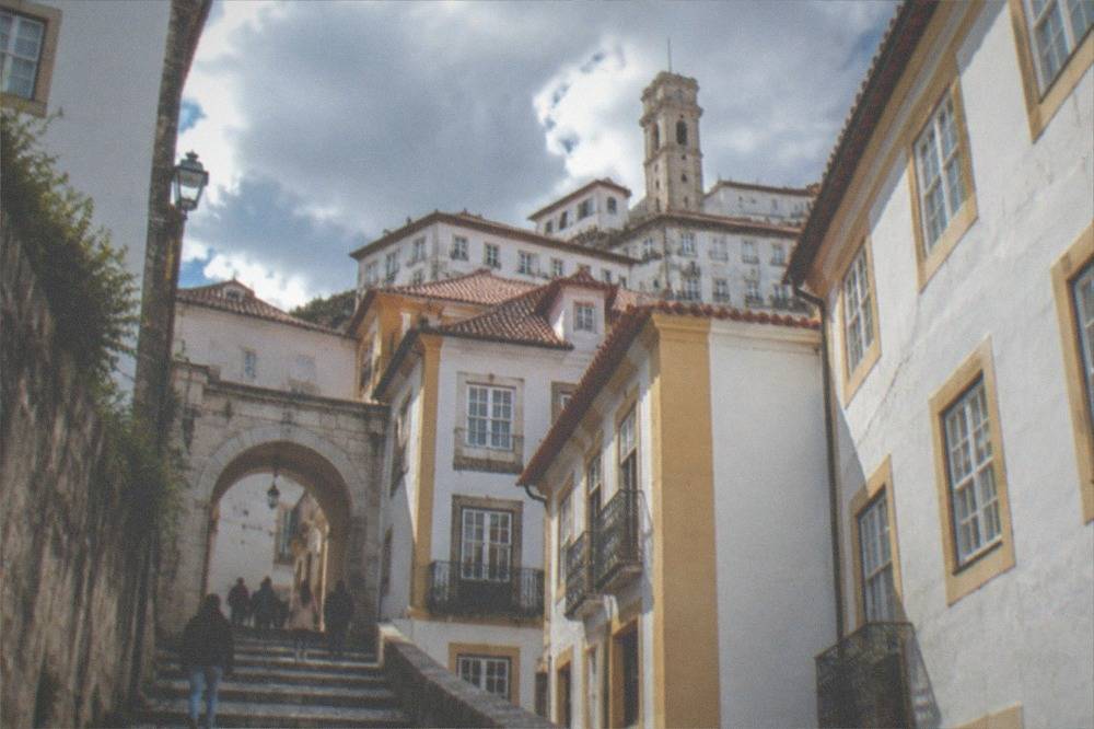 Visitors walking through a stone archway near the university in Coimbra