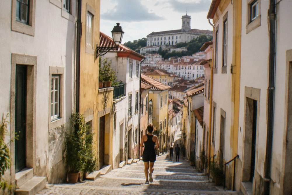 An evening street in central Coimbra with lit windows and stone facades