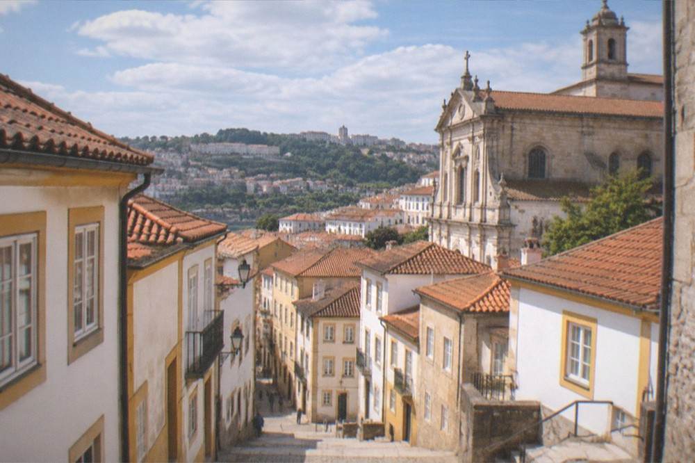 The stone facade of a Coimbra church under a clear sky