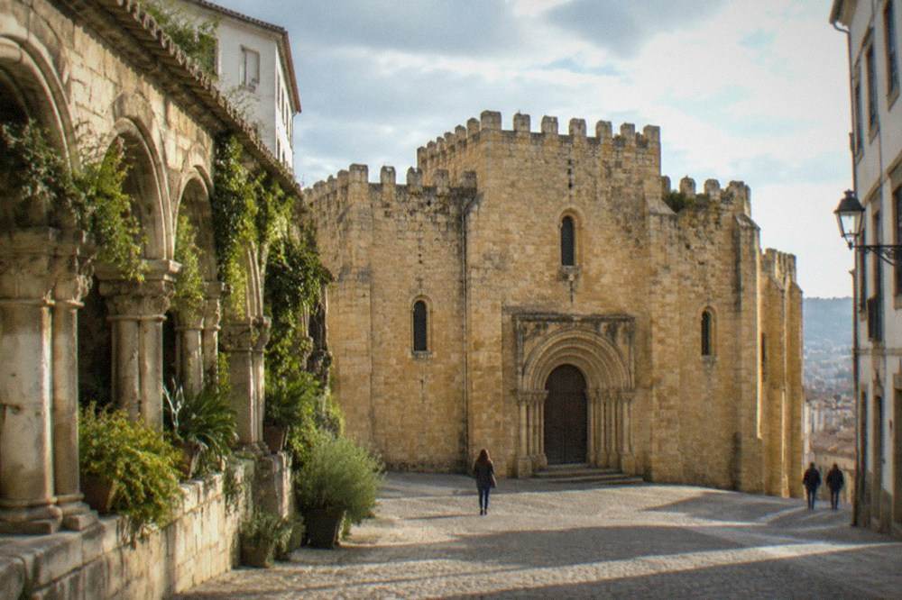The stone cloister of the Sé Velha with plants growing along the arcade walls