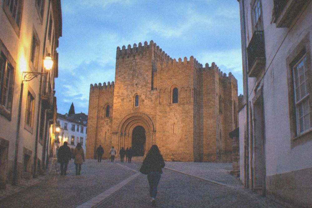 Visitors walking on the cobbled slope leading up toward the old cathedral in warm evening light