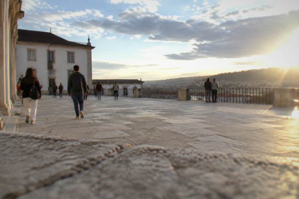 Students and visitors crossing the Paço das Escolas square beside the Via Latina portico