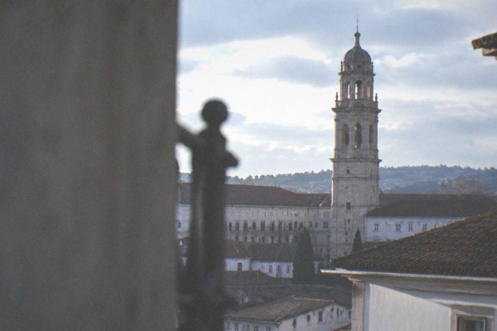 The closed clock tower of the University of Coimbra rising above the palace rooftops