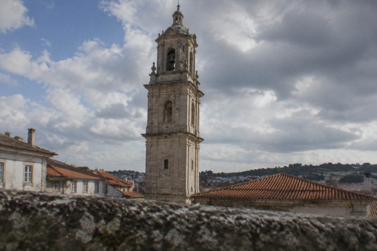 The clock tower of the University of Coimbra rising above the rooftops of the old town