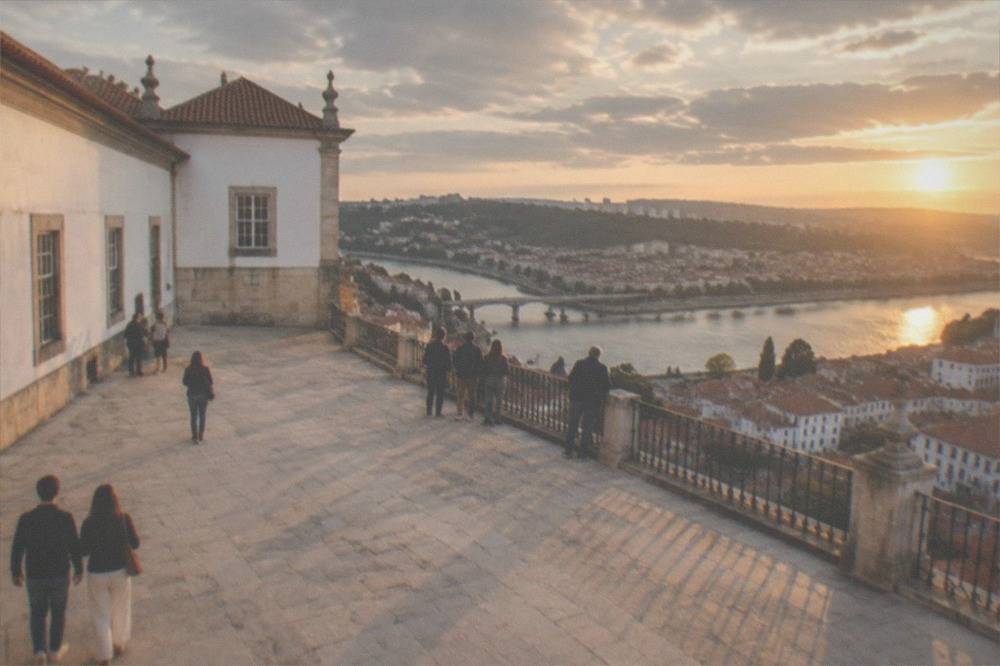 Visitors standing on the terrace beside the Royal Palace looking out over the River Mondego and the rooftops of Coimbra