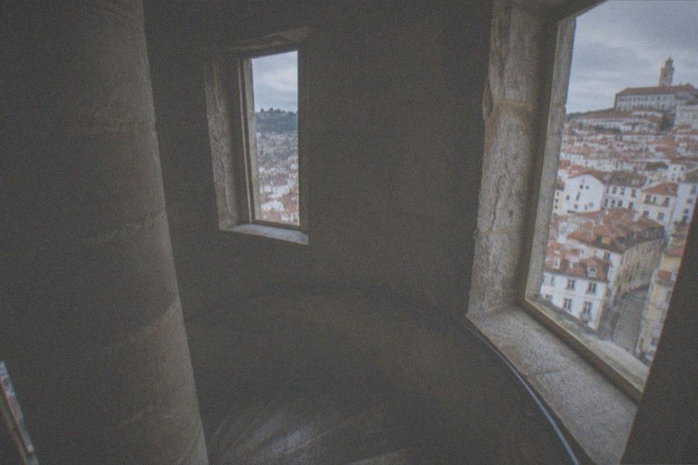 The stone spiral staircase inside a historic Coimbra tower lit by small windows