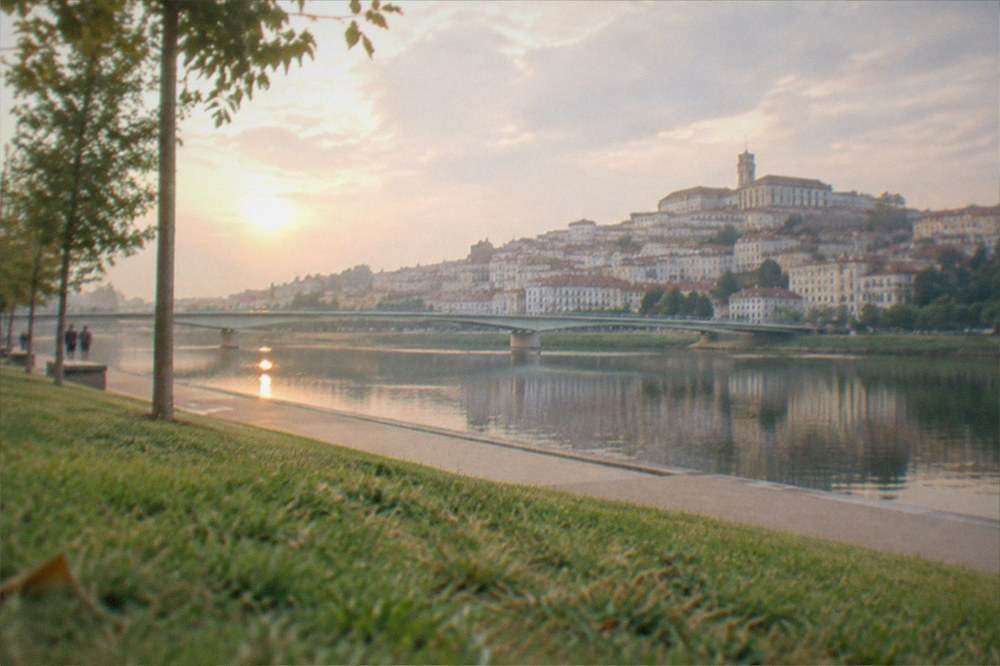 The tower and old town skyline reflected in the River Mondego at sunset from the Santa Clara bank