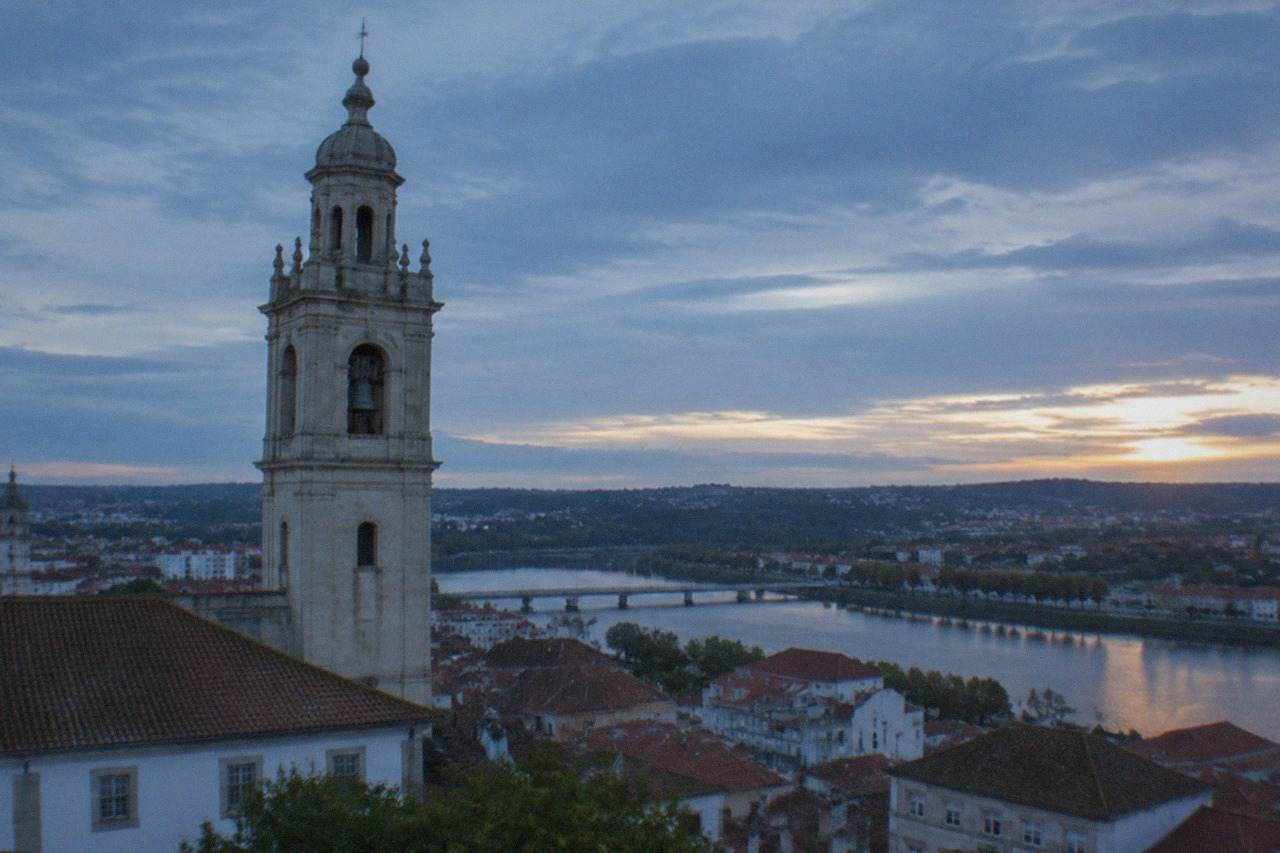View over Coimbra's old town with the university tower rising above red rooftops and the River Mondego in the distance