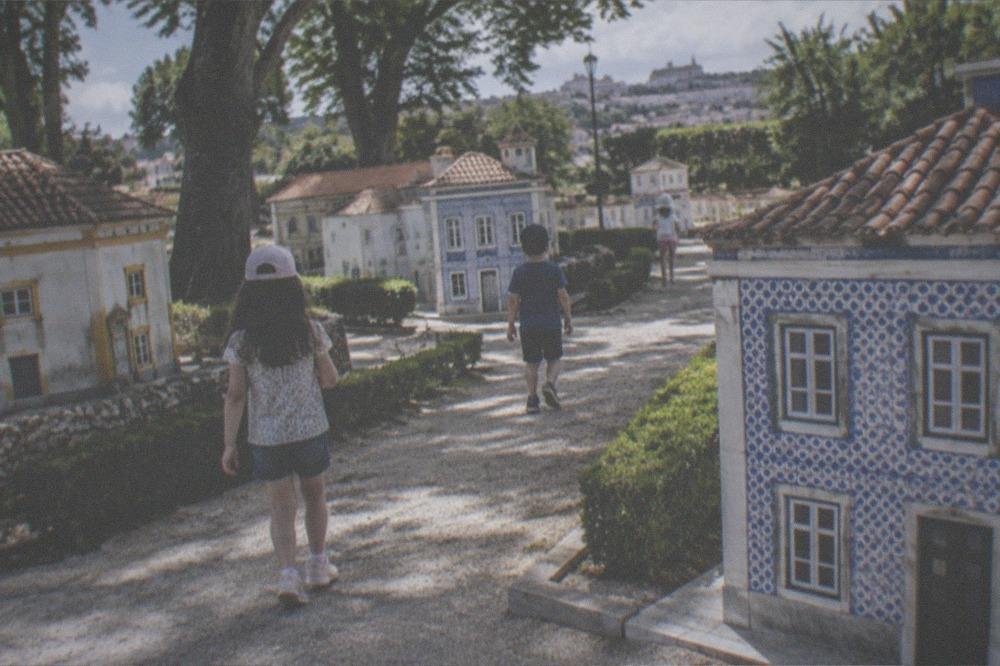 Children walking among the miniature tiled houses of the Portugal dos Pequenitos theme park