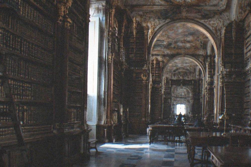 The baroque interior of the Joanina Library with tall wooden bookshelves and painted ceilings