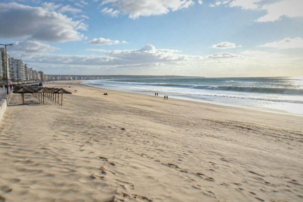 Figueira da Foz seafront promenade with parasols and the wide sandy bay curving to the north
