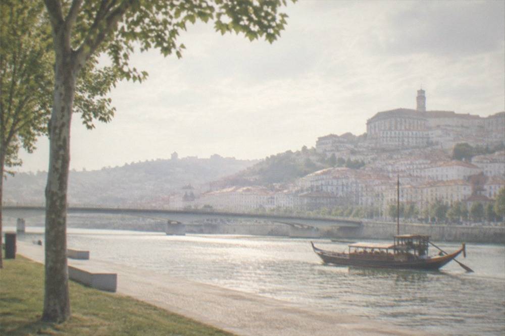 Traditional wooden boat on the River Mondego with Coimbra's old town rising on the far bank