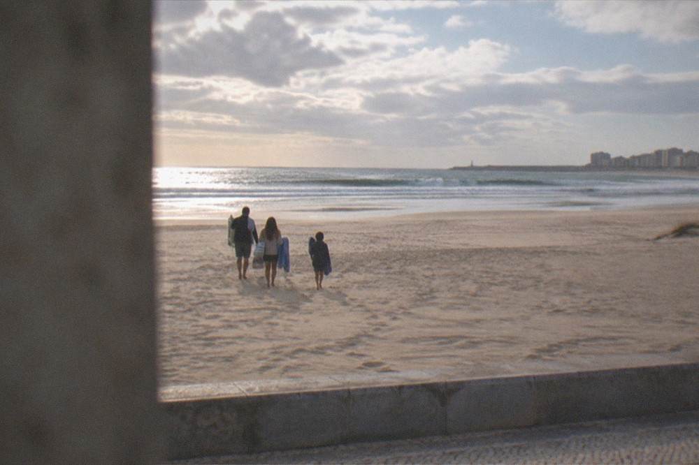 Family walking across warm sand toward the sea with towels and a beach bag at the Atlantic shore