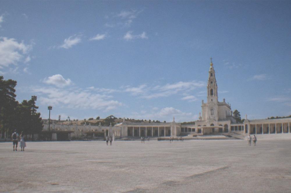 Visitors in light summer clothing walking an open esplanade under a clear sky