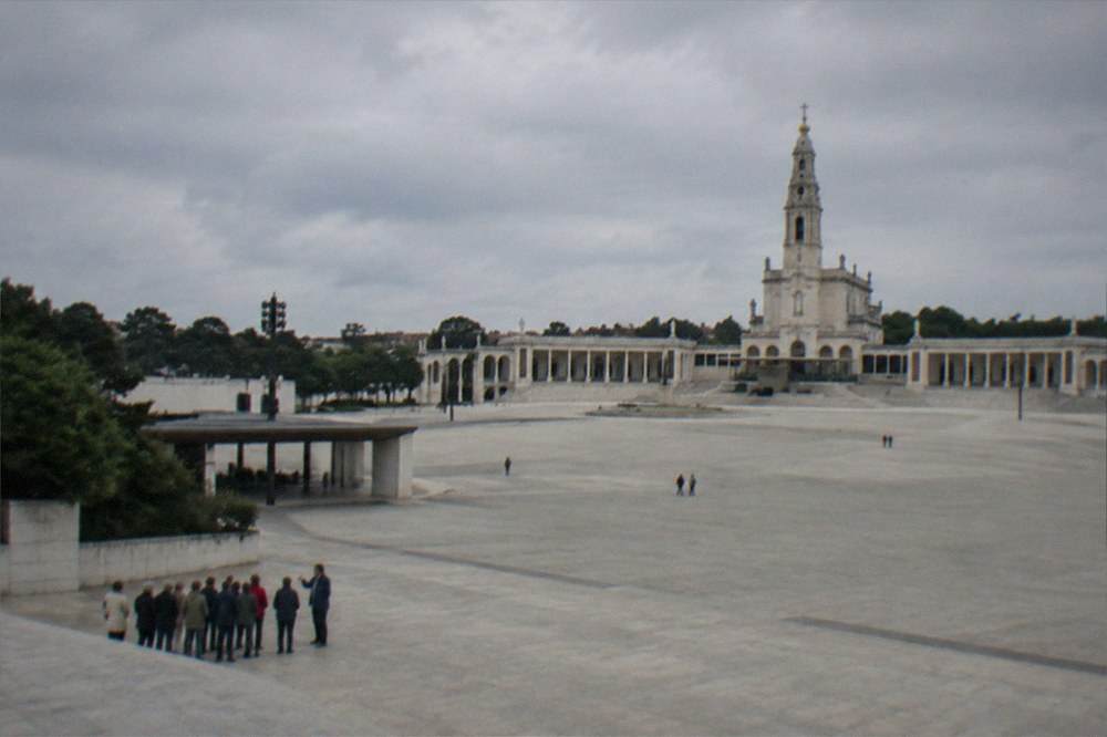 A tour group with a guide pausing at a shaded spot near the basilica