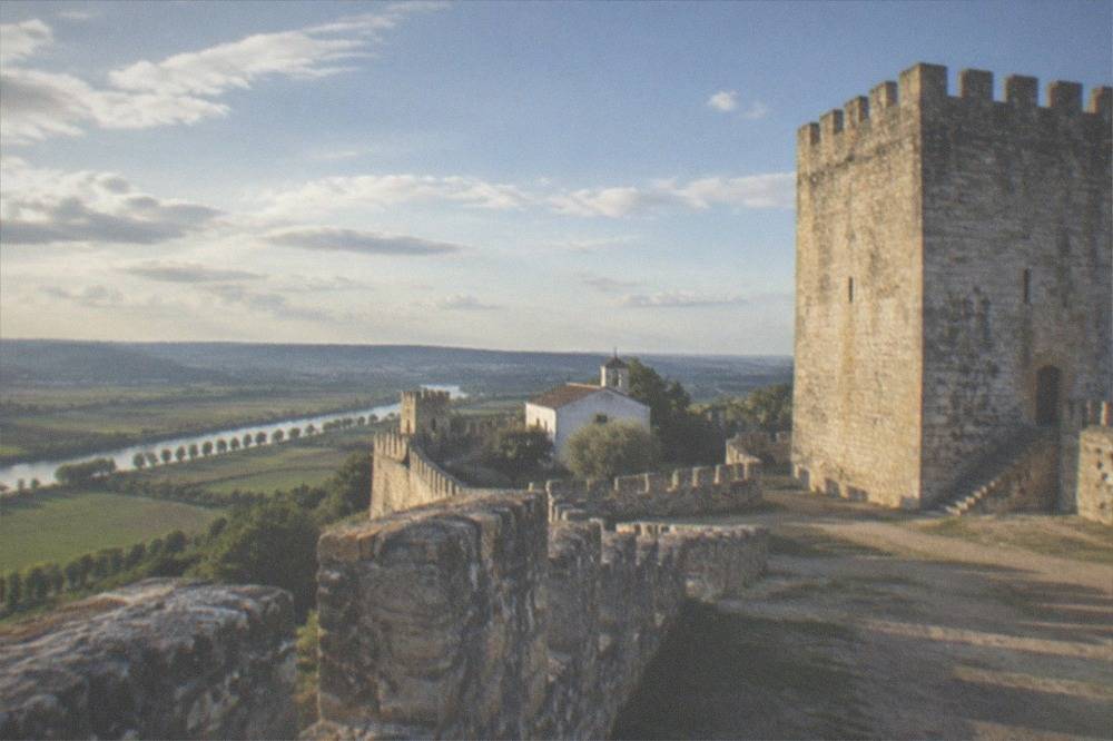 A stone keep tower seen from inside castle walls under a clear sky