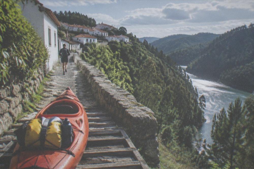 A dry bag and water bottle secured in the stern of a kayak on a wooden slipway