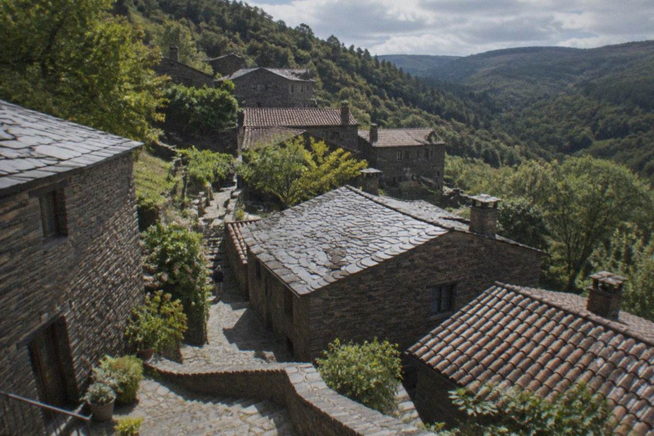 Stone schist village houses with slate roofs on a green mountainside