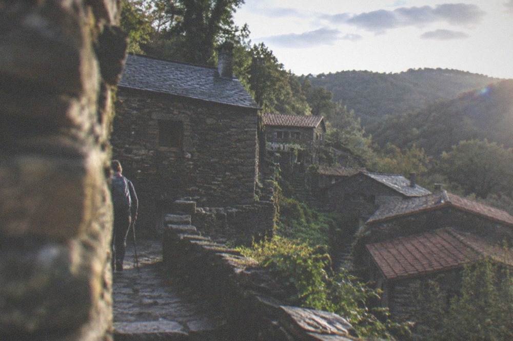Hiker on a stone path between two mountain villages