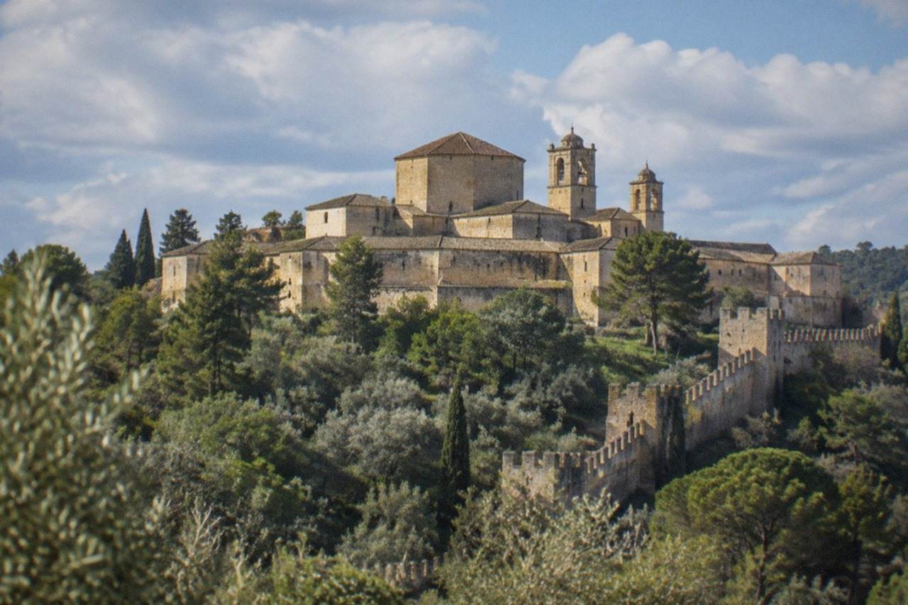 The walled Convent of Christ complex in Tomar seen from a distance with its bell towers above trees