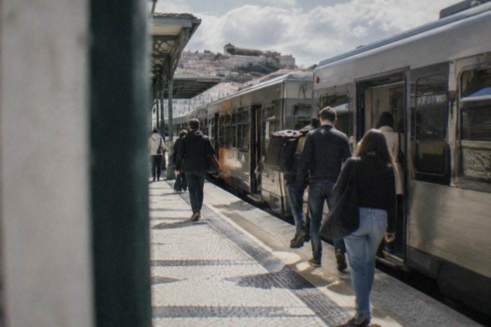 A regional train standing at a Portuguese station platform with passengers boarding