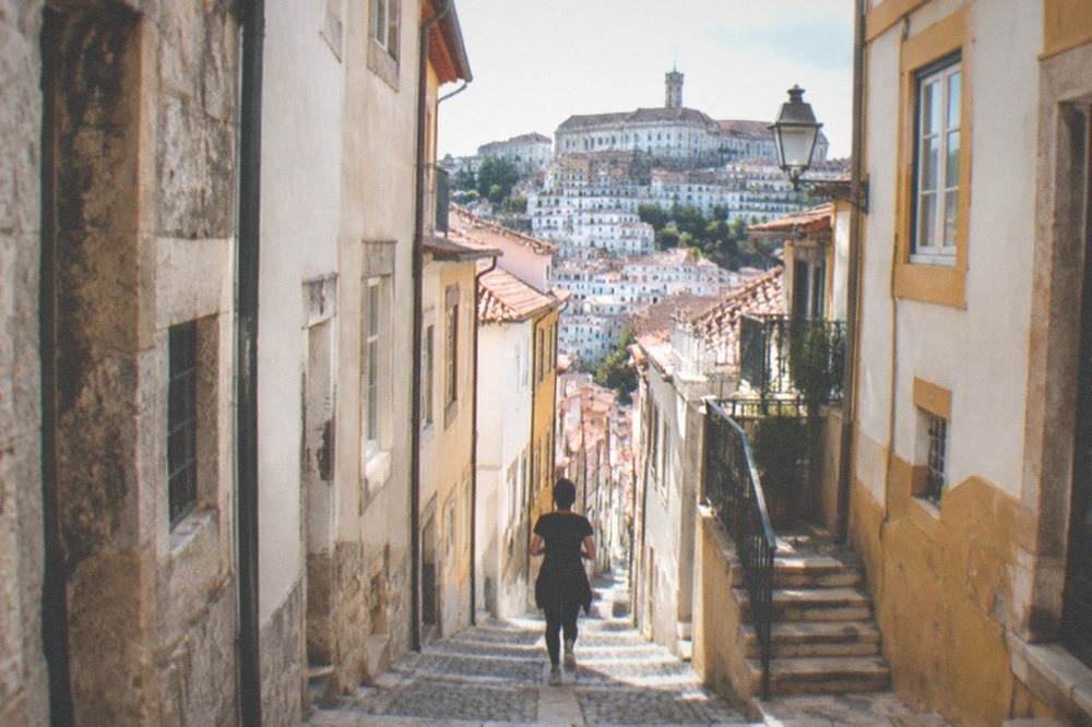 A narrow cobbled street in Coimbra's old town with stone buildings on both sides