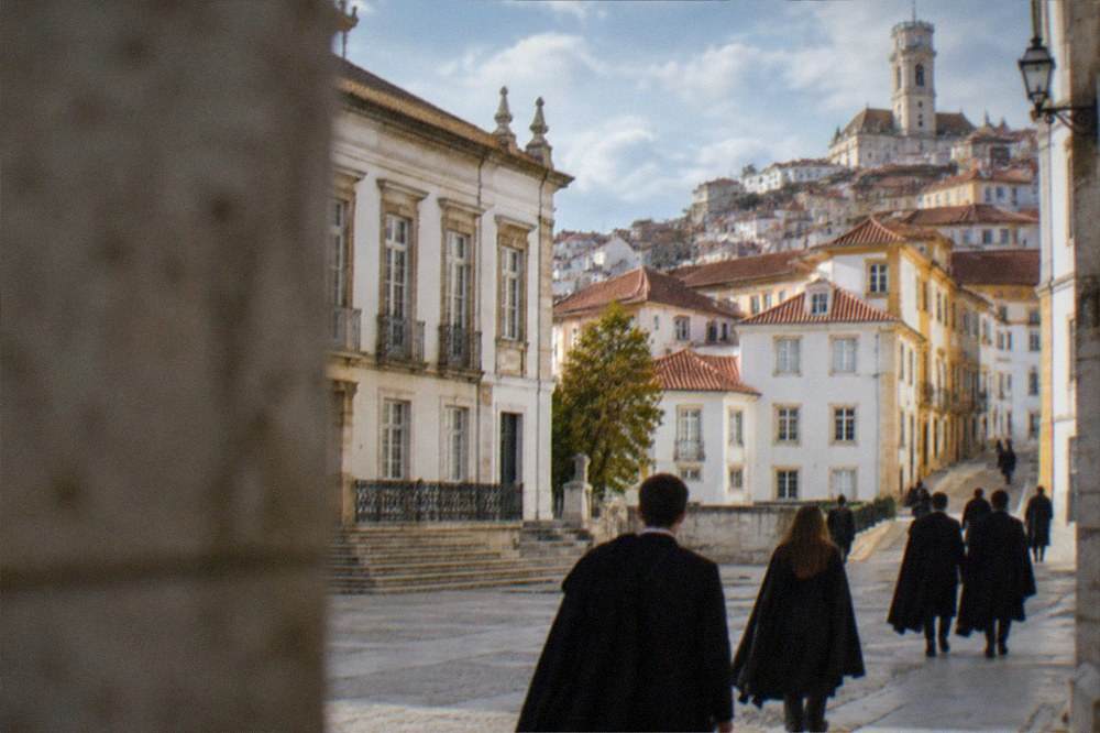 Students in traditional black capes walking through the university square in Coimbra