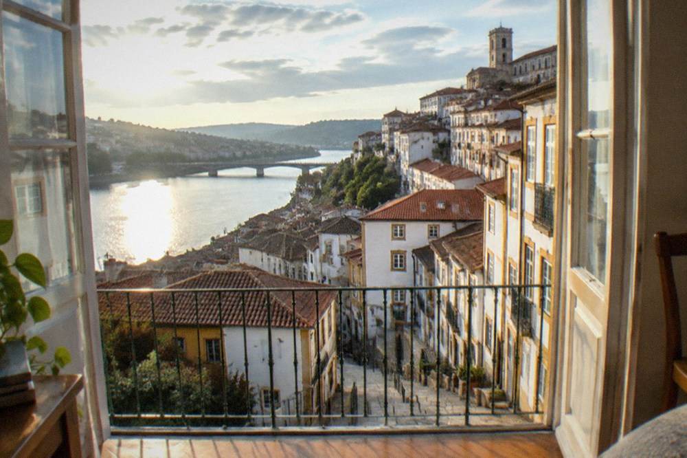 Sunlit apartment interior in Coimbra with wooden floors and a view toward the river