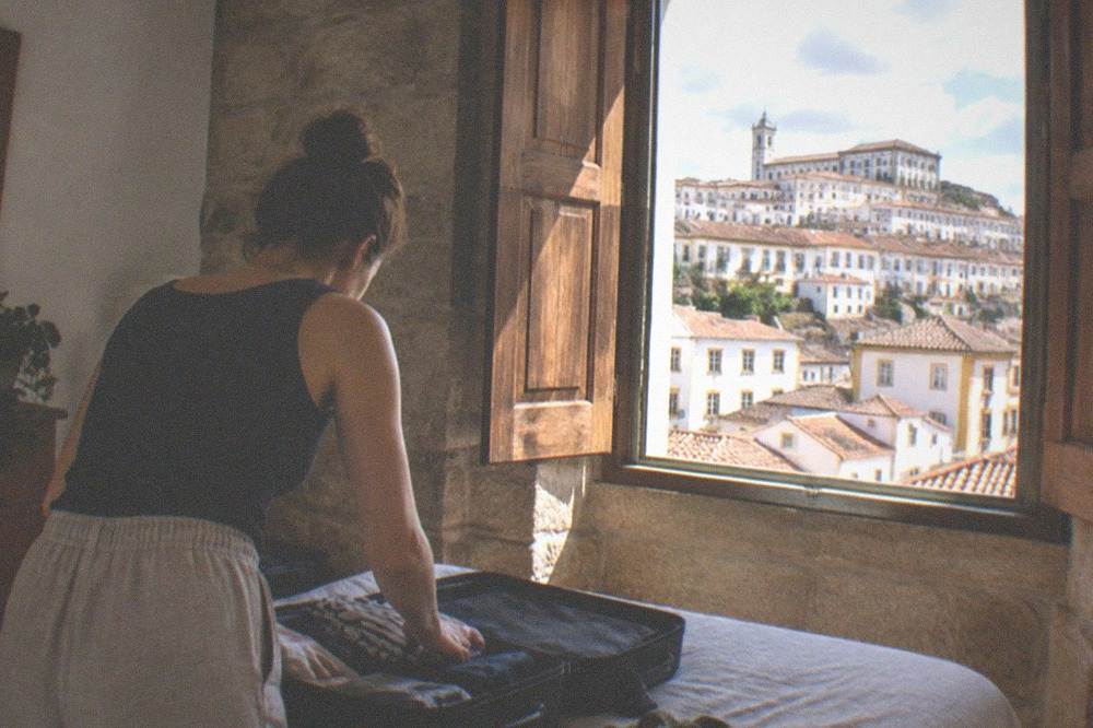Traveller unpacking a suitcase in a Coimbra apartment with thick stone walls and wooden shutters