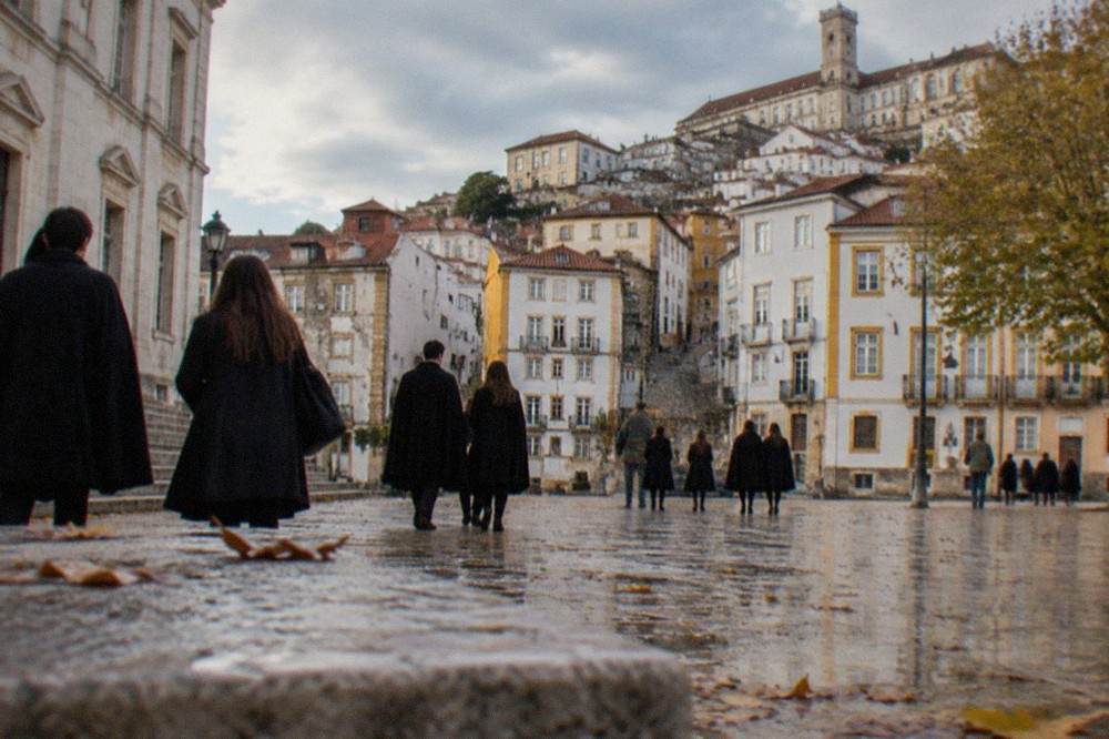 Students in black capes crossing a sunny square near the university in Coimbra