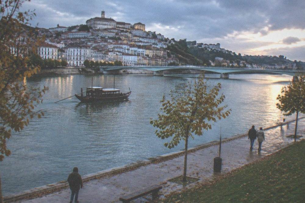 A traditional wooden boat on the Mondego river with Coimbra's old town behind it