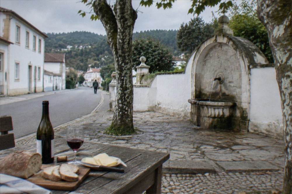 A rustic table set with bread, cheese and an open bottle of red wine