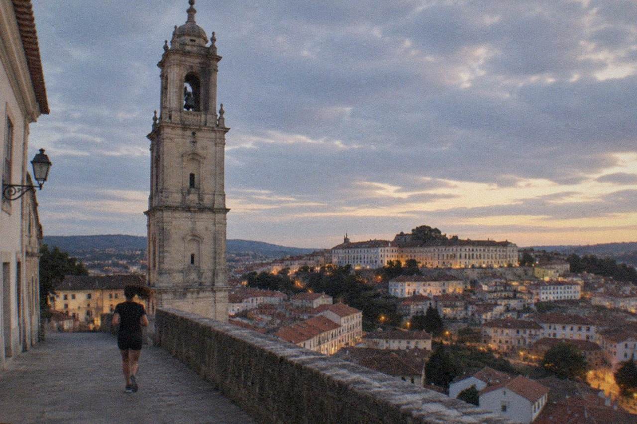 Evening view over the rooftops and lit windows of Coimbra's old town with the university tower rising above the city