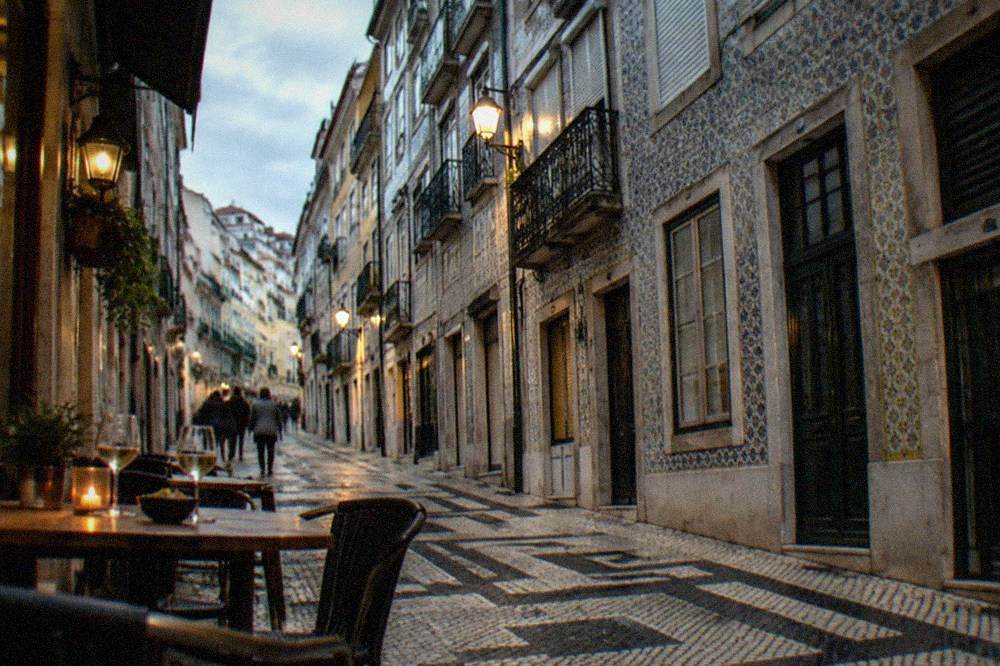 An evening table set outside a small restaurant in a narrow tiled street with warm lamplight