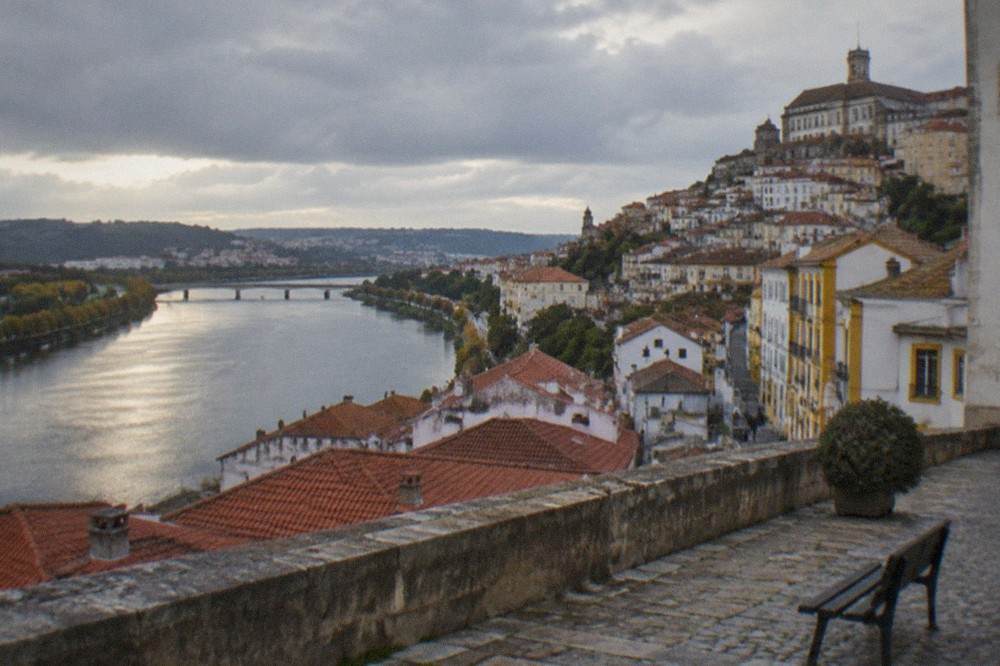 Stone terrace overlooking red rooftops and the river below in Coimbra