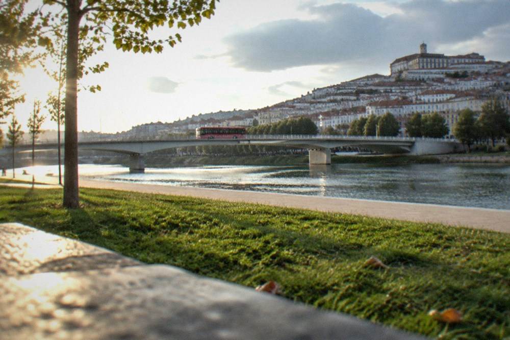 A red city bus crossing a bridge over the River Mondego in Coimbra