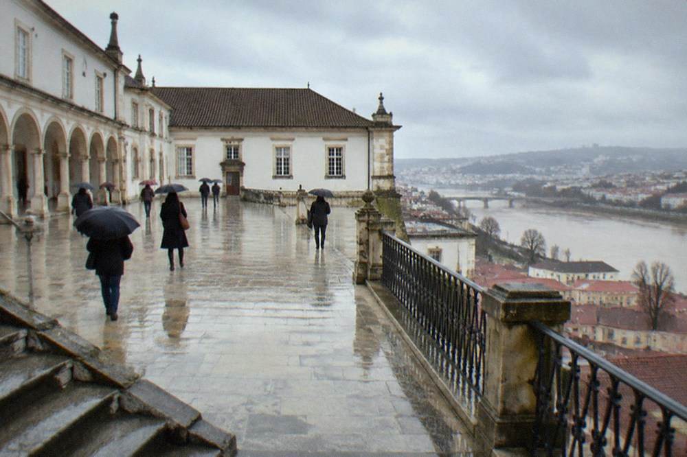 Visitors walking through the arcaded courtyard of the University of Coimbra in winter