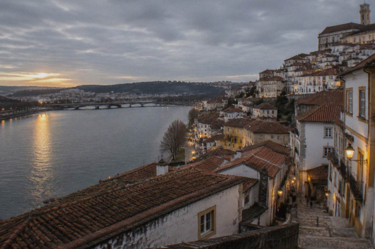 The illuminated old city of Coimbra seen from across the River Mondego at dusk