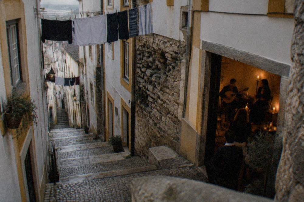 A fado guitarist and singer performing by candlelight in a small Coimbra venue