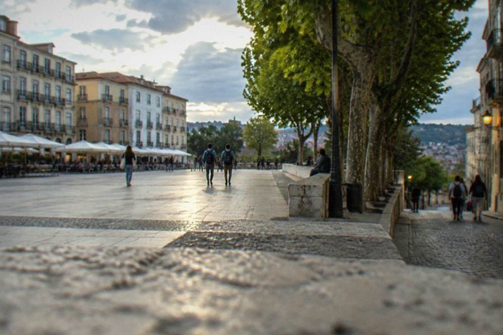 A lit cobbled lane in Coimbra's old town with students walking in the evening