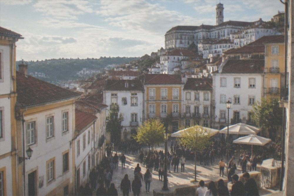 Crowds of students gathered in a lit square in Coimbra in the evening