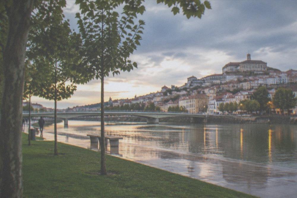 Lights of Coimbra's old town reflecting in the River Mondego after dark