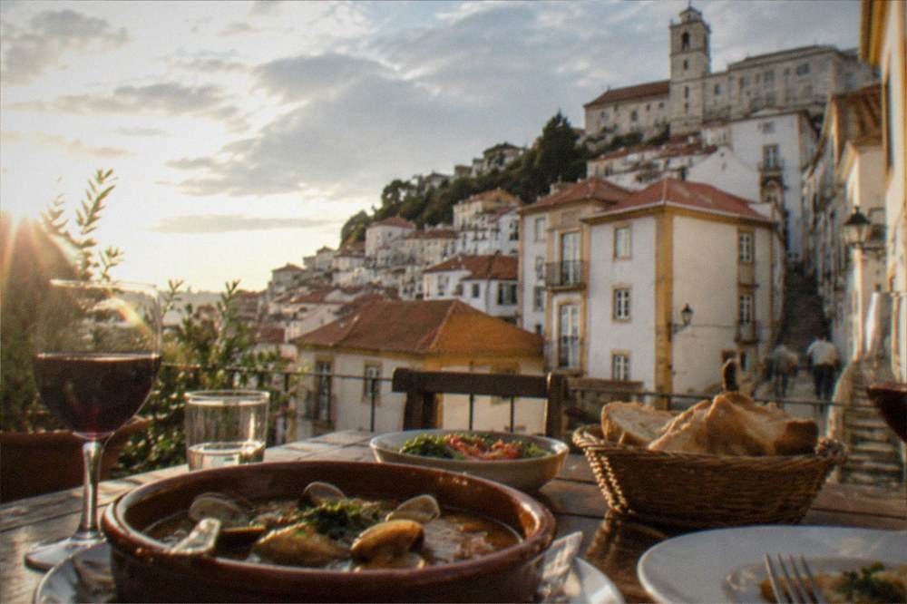 A dinner table with wine and Portuguese dishes on a lit terrace in Coimbra