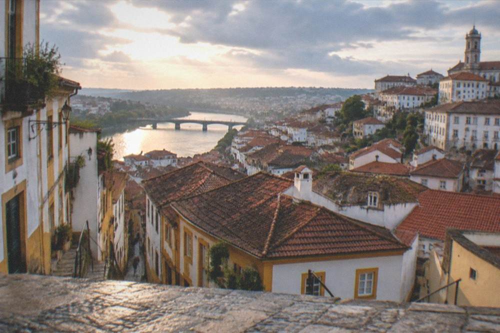 A view over the rooftops of Coimbra with the River Mondego in the distance