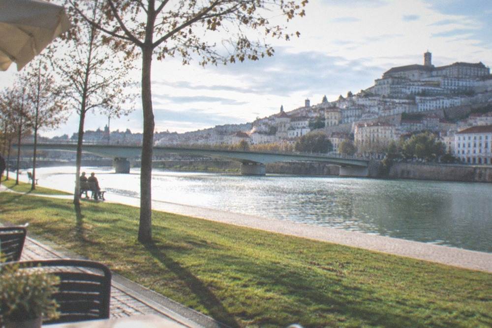 A sunny terrace above the Mondego river with the old town bridge in the background