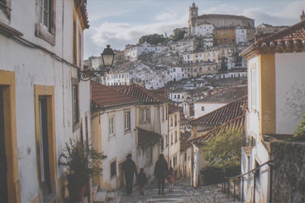 A family walking among miniature Portuguese buildings at an open-air park