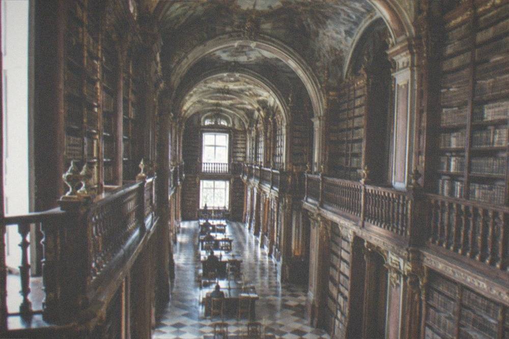 The baroque interior of the Joanina Library with tall wooden bookshelves and painted ceilings